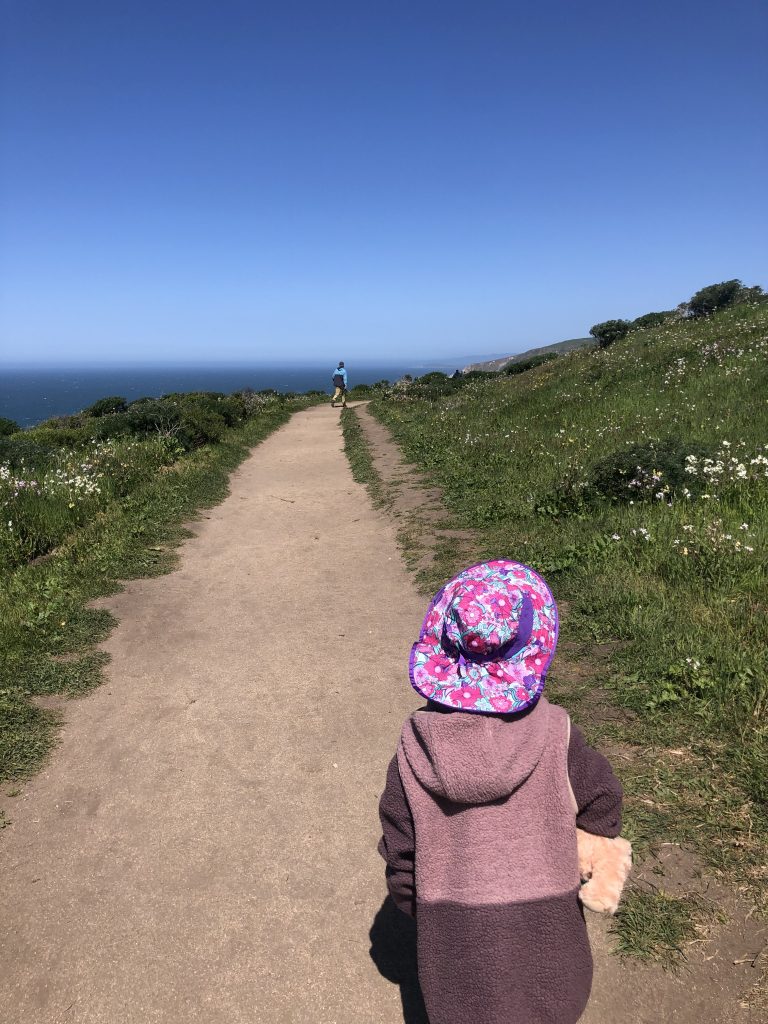 A child in a hat hiking the Tomales Point Trail in Point Reyes National Seashore
