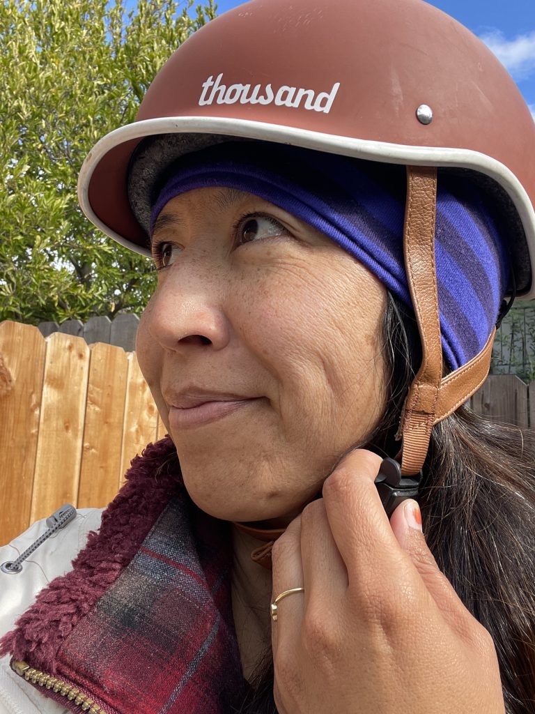 Adult wearing a purple Smartwool headband under a bike helmet