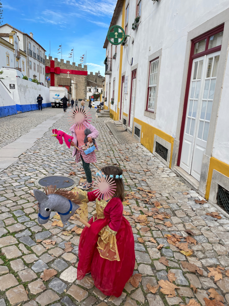Two girls in princess dresses shopping on cobble stone streets outside the walls of Obidos, Portugal