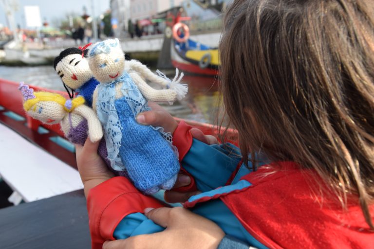 A child holding three knitted dolls in Aveiro Portugal