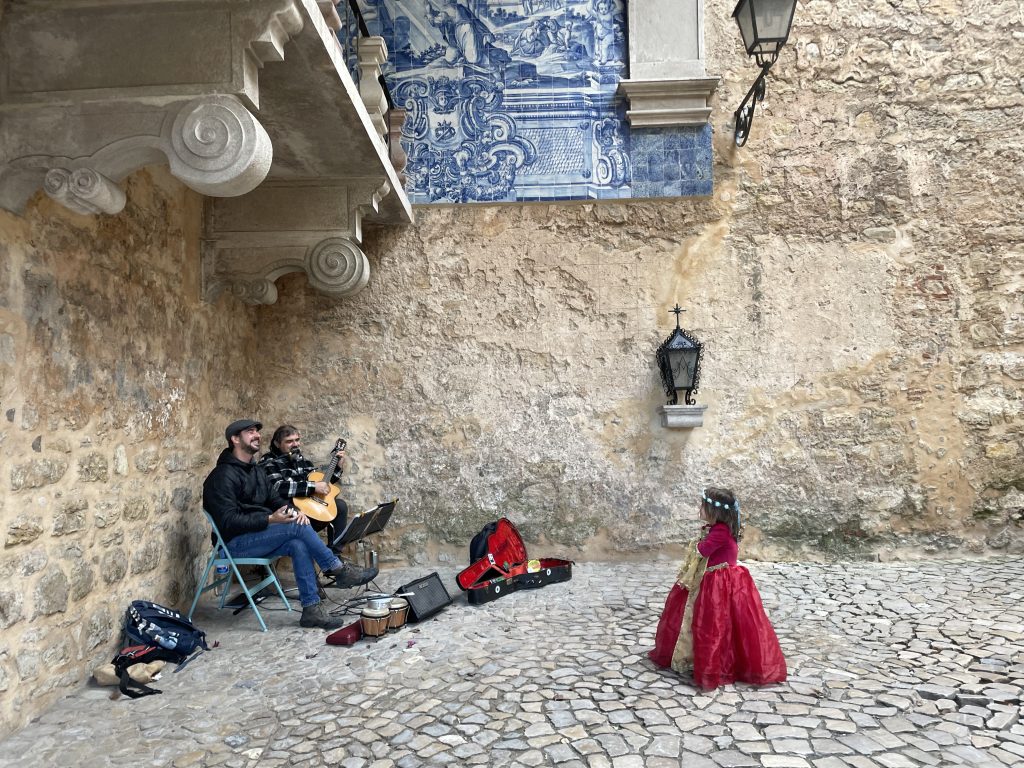 Child in a princess dress dancing to music in Obidos, Portugal's Porta da Vila