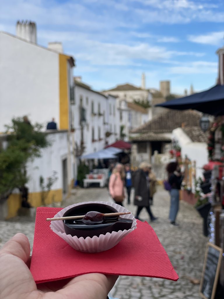 A hand holding a chocolate glass of ginja in Obidos, Portugal