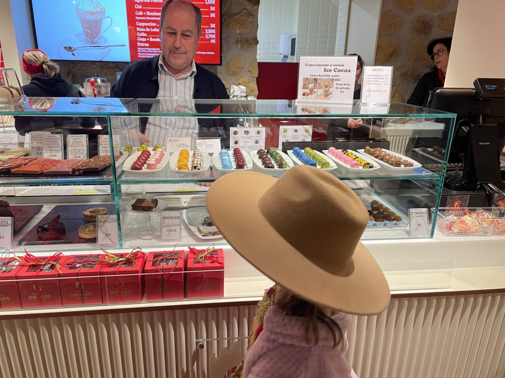 A child in a brown hat ordering chocolate in Obidos portugal