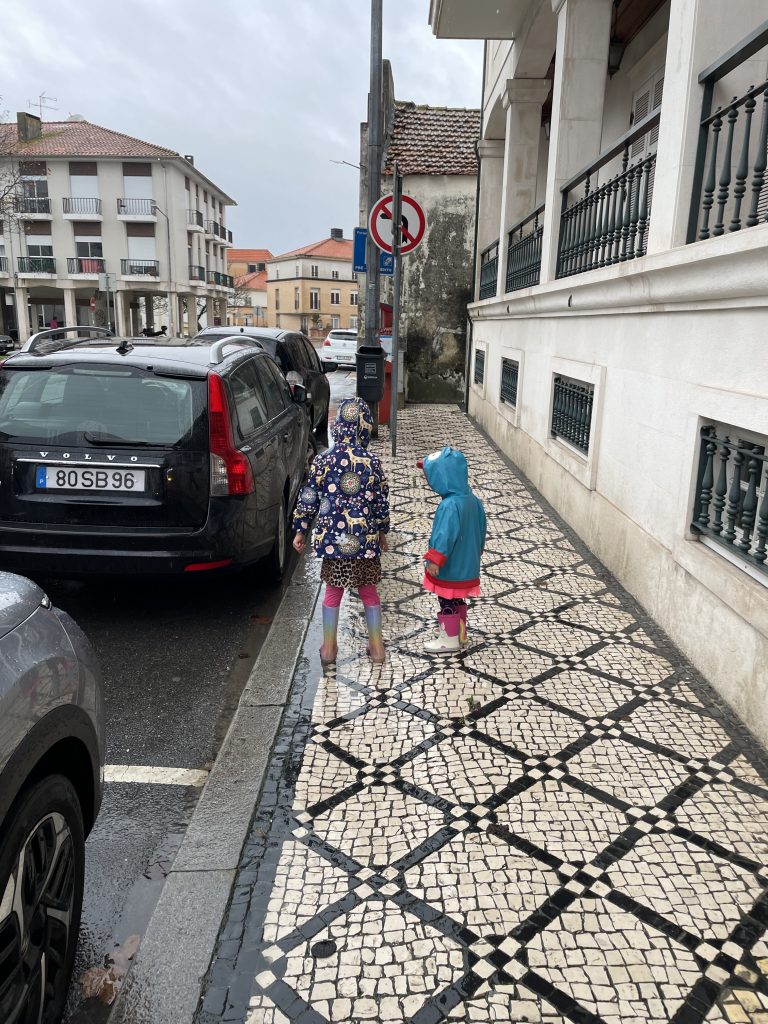 Two children walking in Aviero, Portugal with rain coats