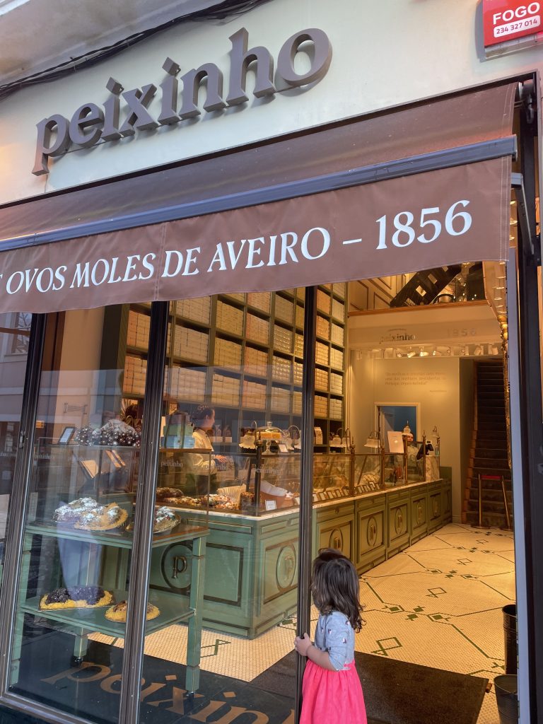 A child standing in front of the Peixinho store in Aviero