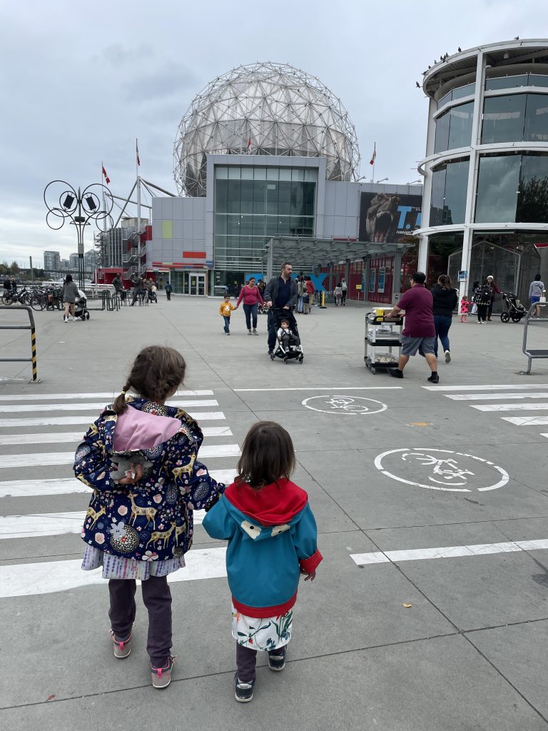 Two children walking to the Science museum wearing rain coats in Vancouver, BC Canada