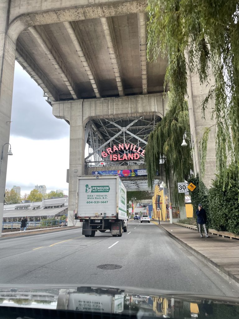 A truck driving under the Granville Island sign in Vancouver, BC, Canada