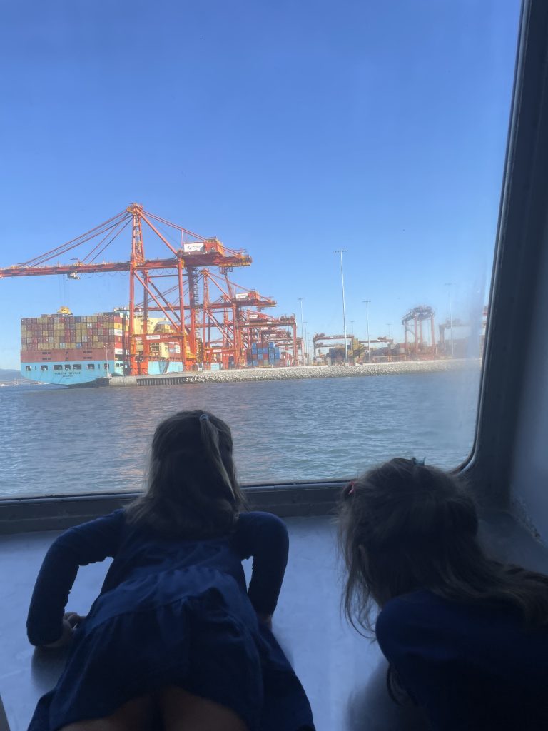 Two children looking out of a window on the Seabus at container ships in Vancouver BC Canada