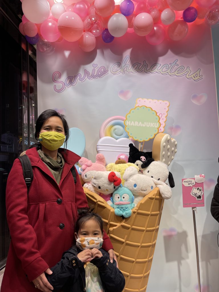 Jelly and her daughter stand in front of a giant plastic ice cream cone full of Sanrio characters in Tokyo.