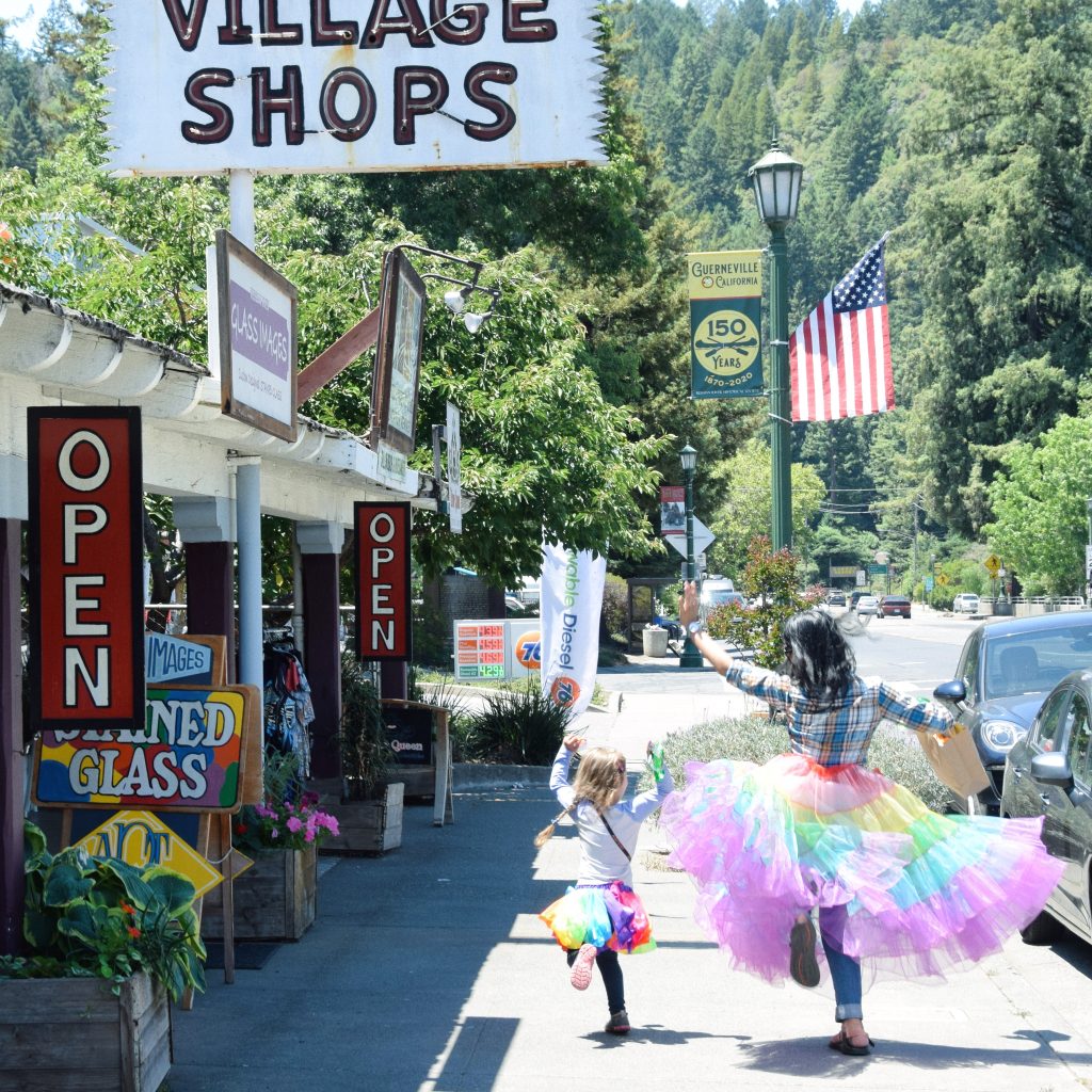 An adult and child dancing in a rainbow tutu in Guerneville California