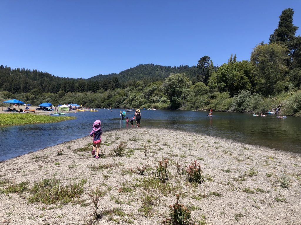 A child walking down the rocky shore of the Russian River at Casini Ranch Family Campground in Duncan Mills