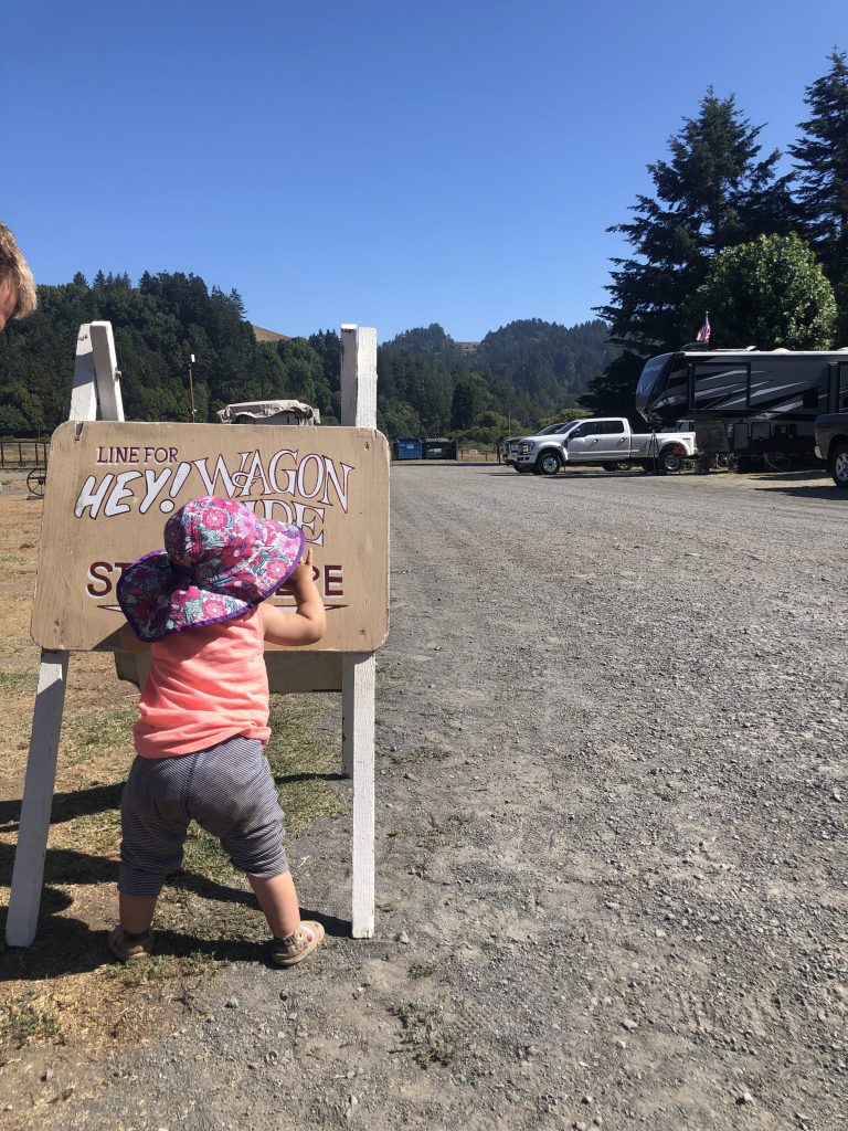 A child standing by the sign waiting for the hayride at Casini Ranch Family Campground in Duncan Mills