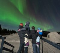 A family looking at the Northern Lights in Fairbanks, Alaska at Borealis Basecamp