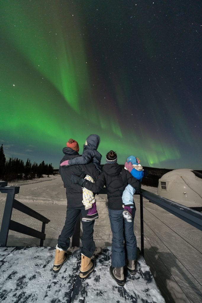 A family looking at the Northern Lights in Fairbanks, Alaska at Borealis Basecamp