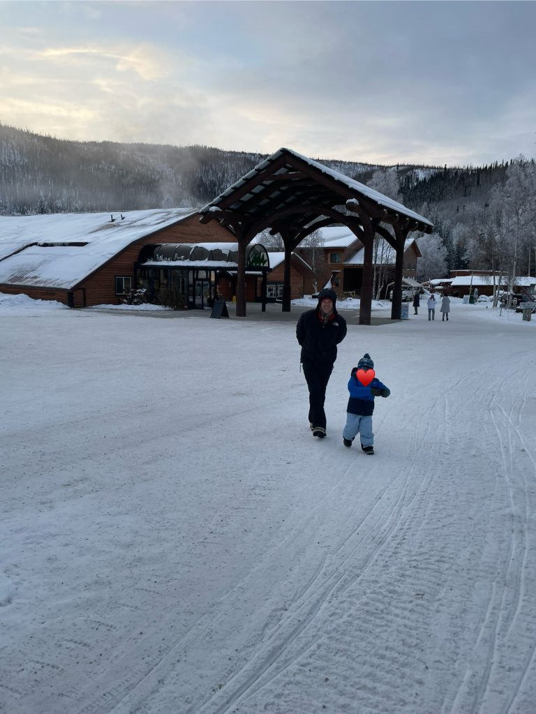 An adult and child walking in Chena Hot Springs Resort in the snow