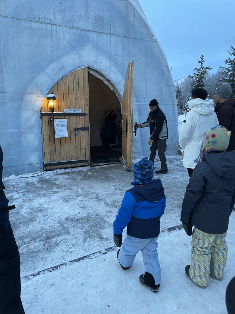 Wide wooden doors opening to let a child into the Ice Museum at Chena Hot Springs in Fairbanks, Alaska