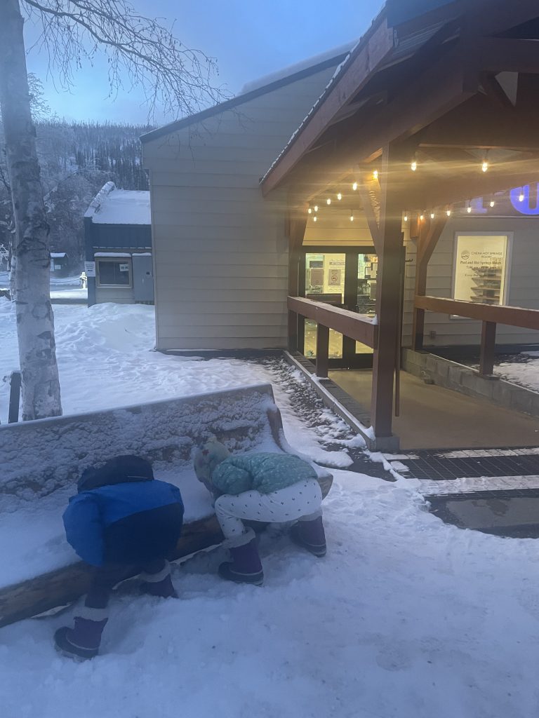 Two kids eating snow outside of the pool house at Chena Hot Springs in Fairbanks Alaska