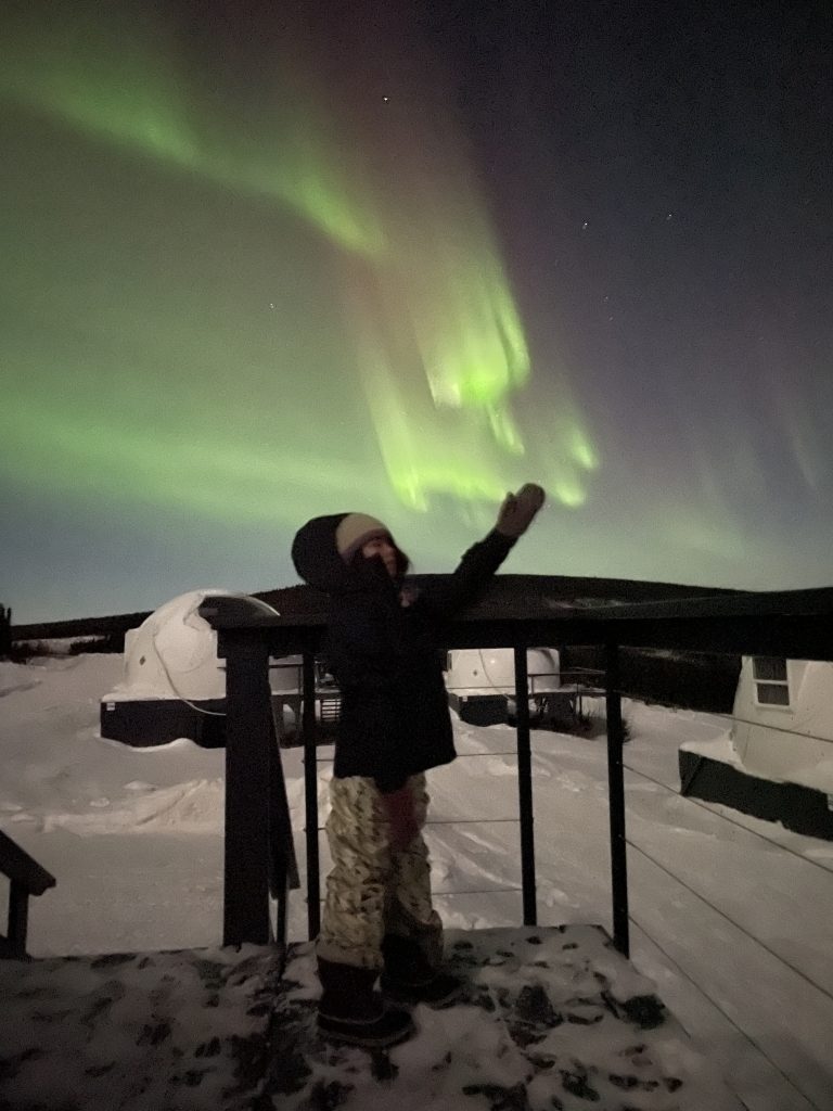 A child's silhouette in front of the northern lights at Borealis Basecamp in Fairbanks Alaska