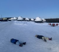 Two children lying on the snow at Borealis Basecamp in Fairbanks Alaska