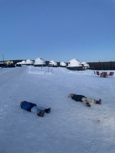 Two children lying on the snow at Borealis Basecamp in Fairbanks Alaska