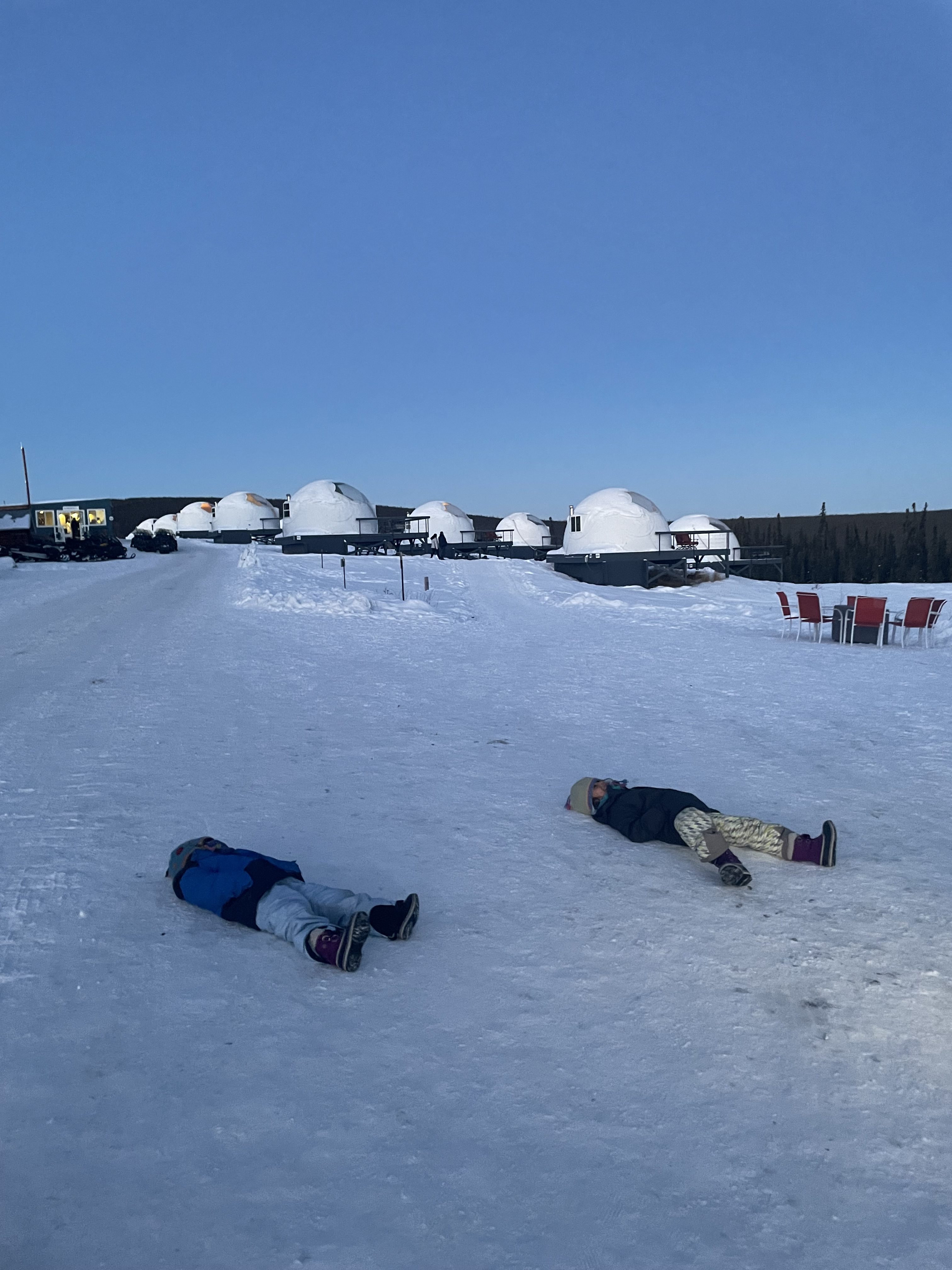 Two children lying on the snow at Borealis Basecamp in Fairbanks Alaska