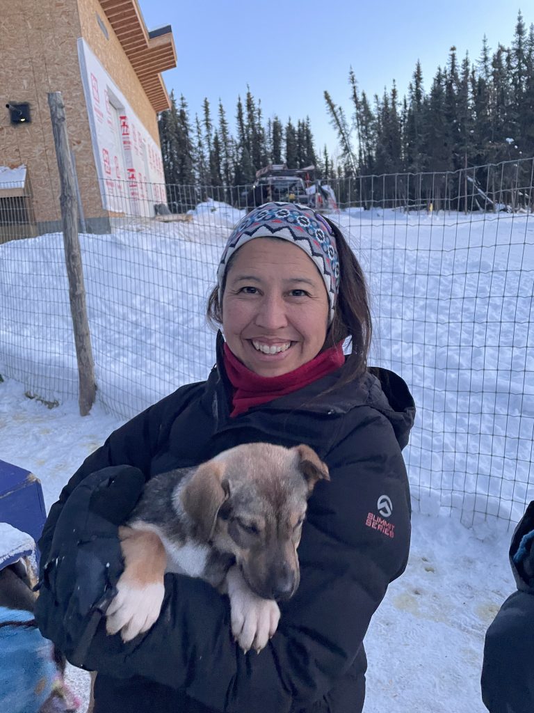 A woman holding a sled puppy at Borealis Basecamp in Fairbanks Alaska