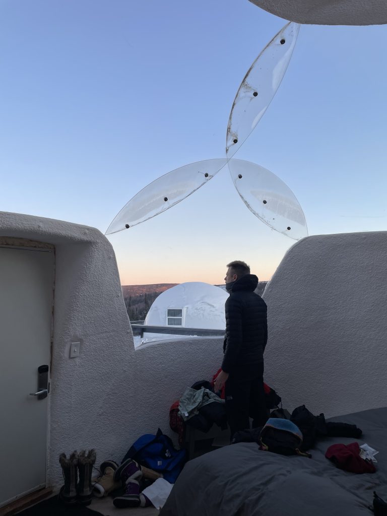 A man looking out of the igloo window at borealis basecamp in Fairbanks, Alaska