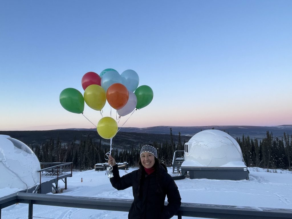 A woman holding balloons for her birthday at Borealis Basecamp in Fairbanks Alaska