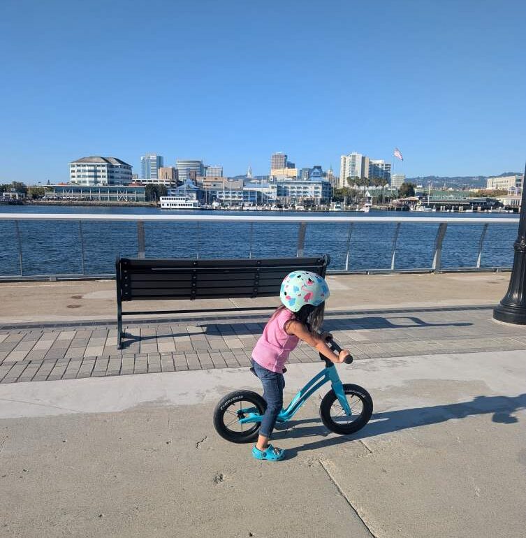 A child riding a teal Hornit AIRO balance bike in Alameda near Bohol Circle Park