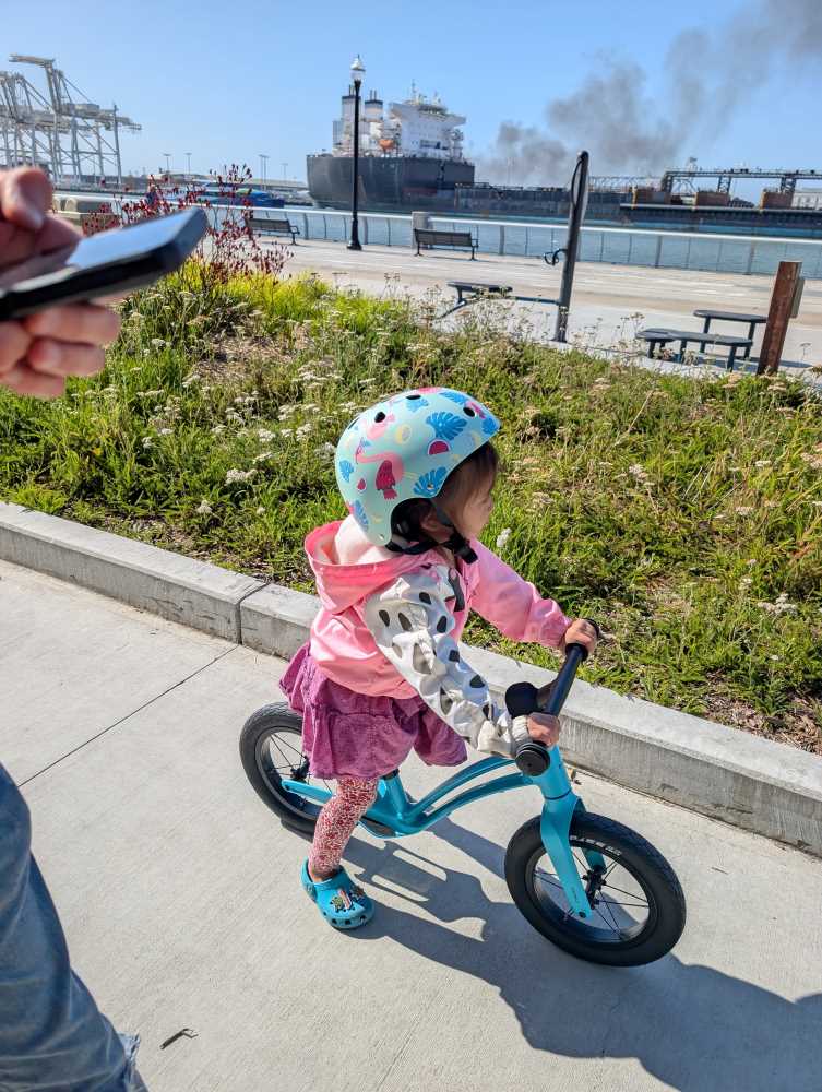 A child riding a hornit airo balance bike in blue along the estuary of Alameda Island