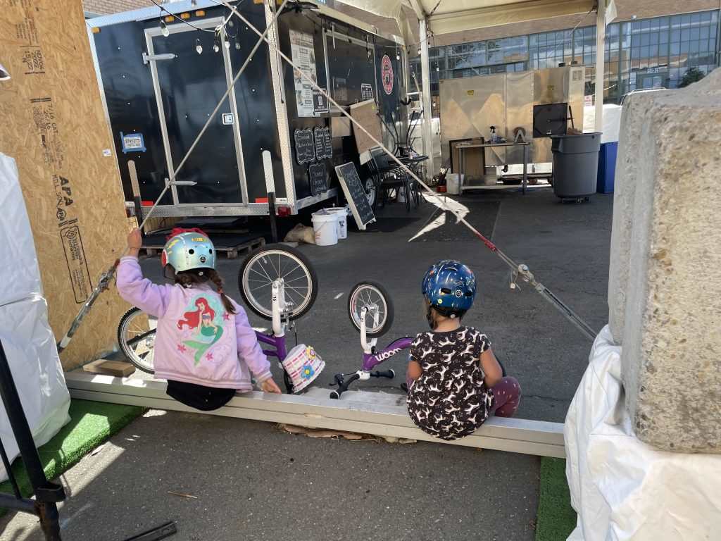 Two children with bike helmets on playing with their woom bikes upside down