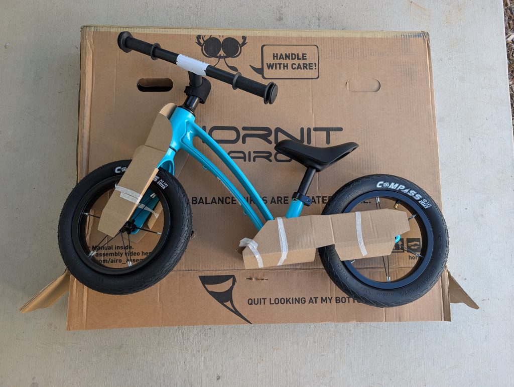 A Hornit Airo balance bike on top of a large cardboard after it was shipped and unboxed