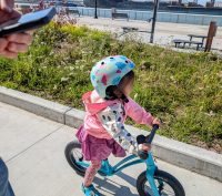 A child riding a hornit airo balance bike in blue along the estuary of Alameda Island