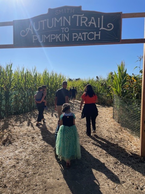 Family pushing a wagon through the entrance to the Autumn Trail at Smith Family Farms in Brentwood, CA