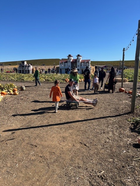 An adult pulling a grown up with a cast at Three Nunns Farm in Brentwood, CA