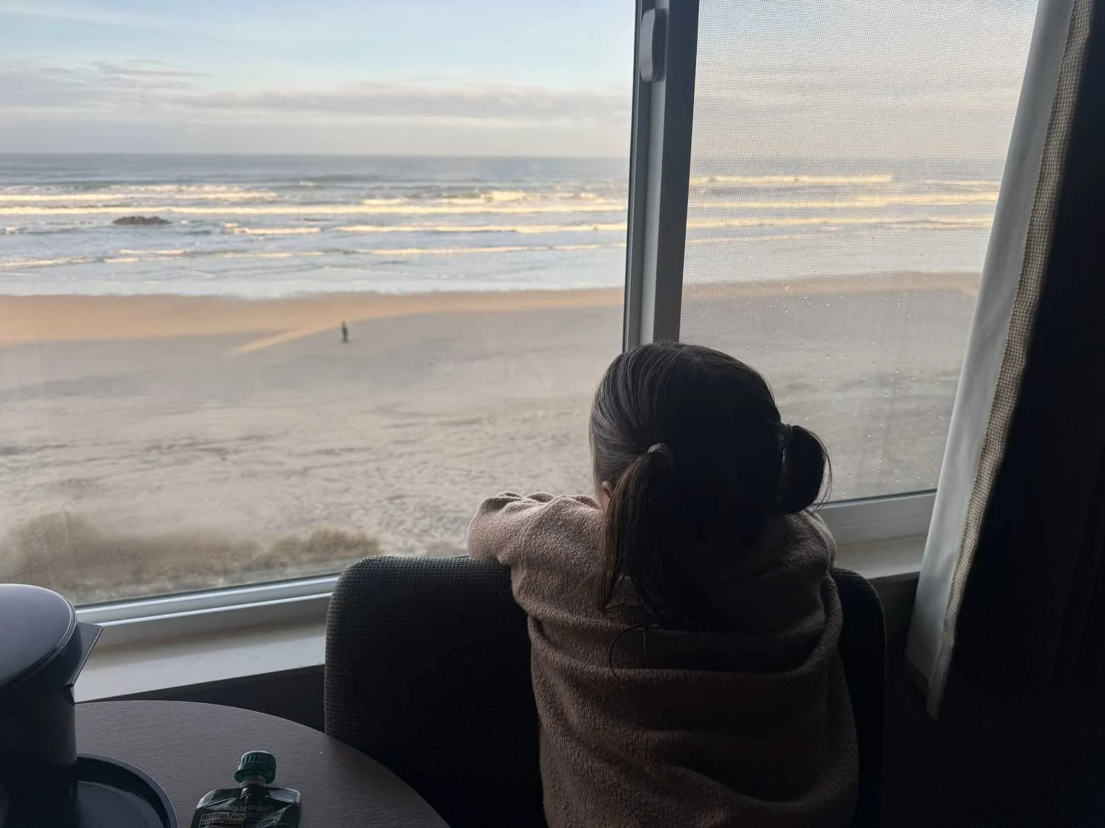 A child with pig tails looking through a window at Chinook Winds Casino Resort in Lincoln City, OR at the Pacific Ocean