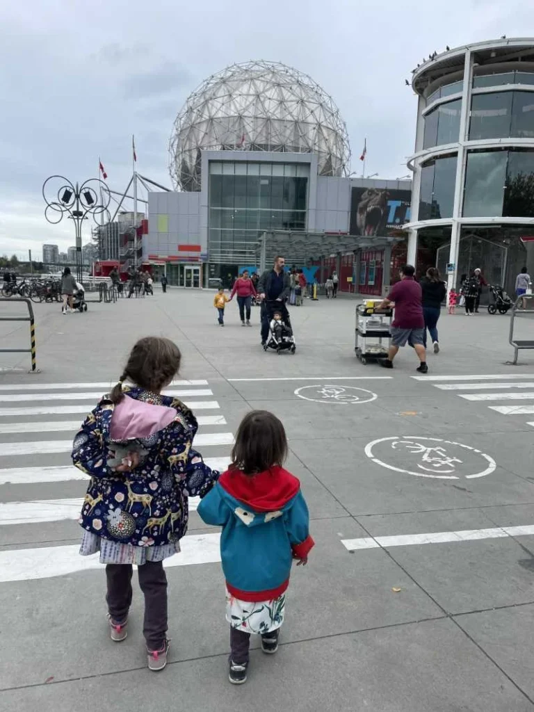 Two young children walking towards Science World in Vancouver, Canada